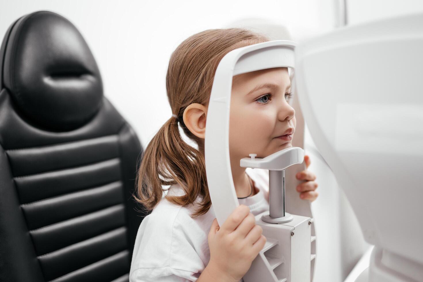 Close-up of a little girl with deep eyes undergoing vision diagnostics using a slit lamp in an ophthalmology clinic. A perfect moment highlighting the importance of caring for children's vision photo