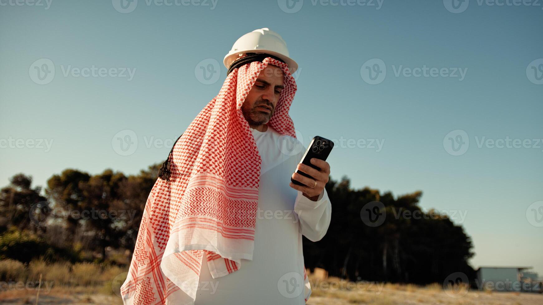 Sheik With Safety Helmet Looking At The Phone photo