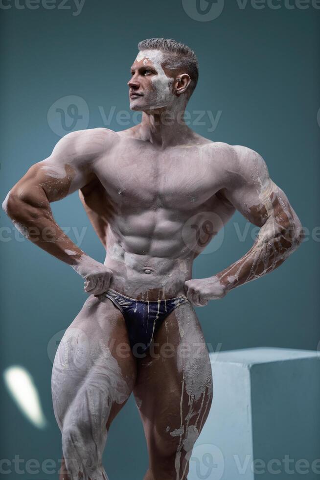 Muscular man with perfect abs posing at studio photo