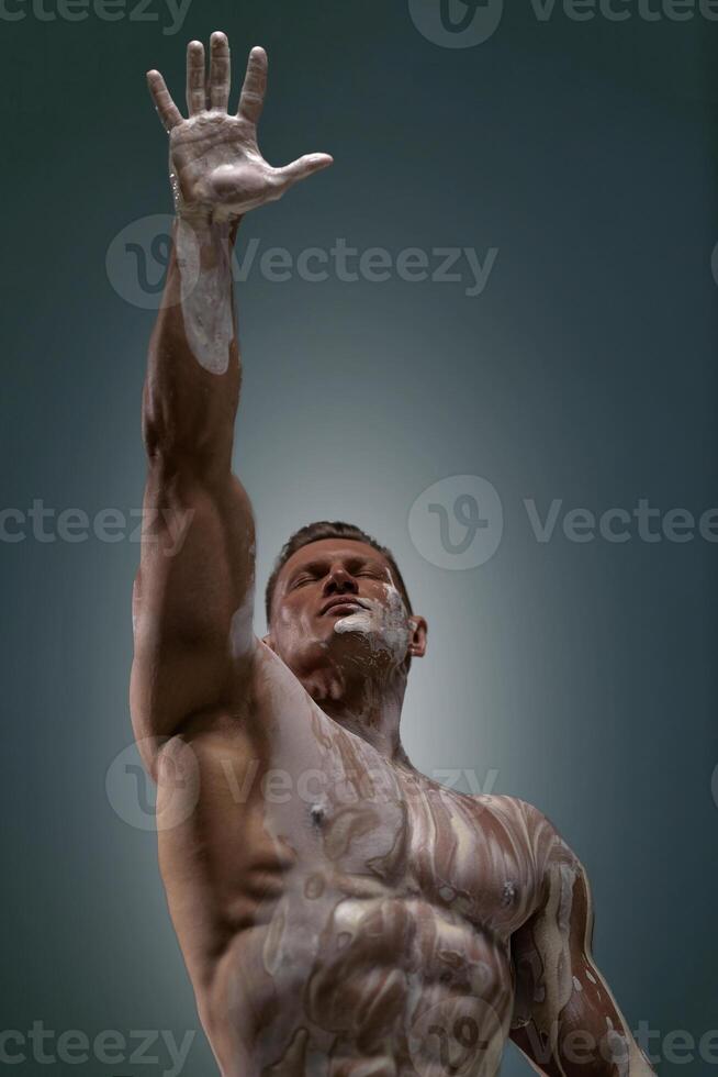 Athletic man posing at the studio with his arm up photo