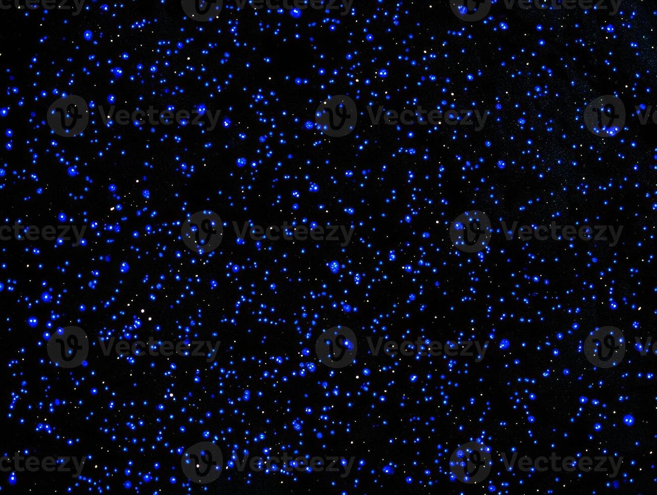 Delicate blue particles illuminate the darkness, creating an enchanting cosmic pattern reminiscent of stars twinkling in the vast night sky, captivating the viewer. photo