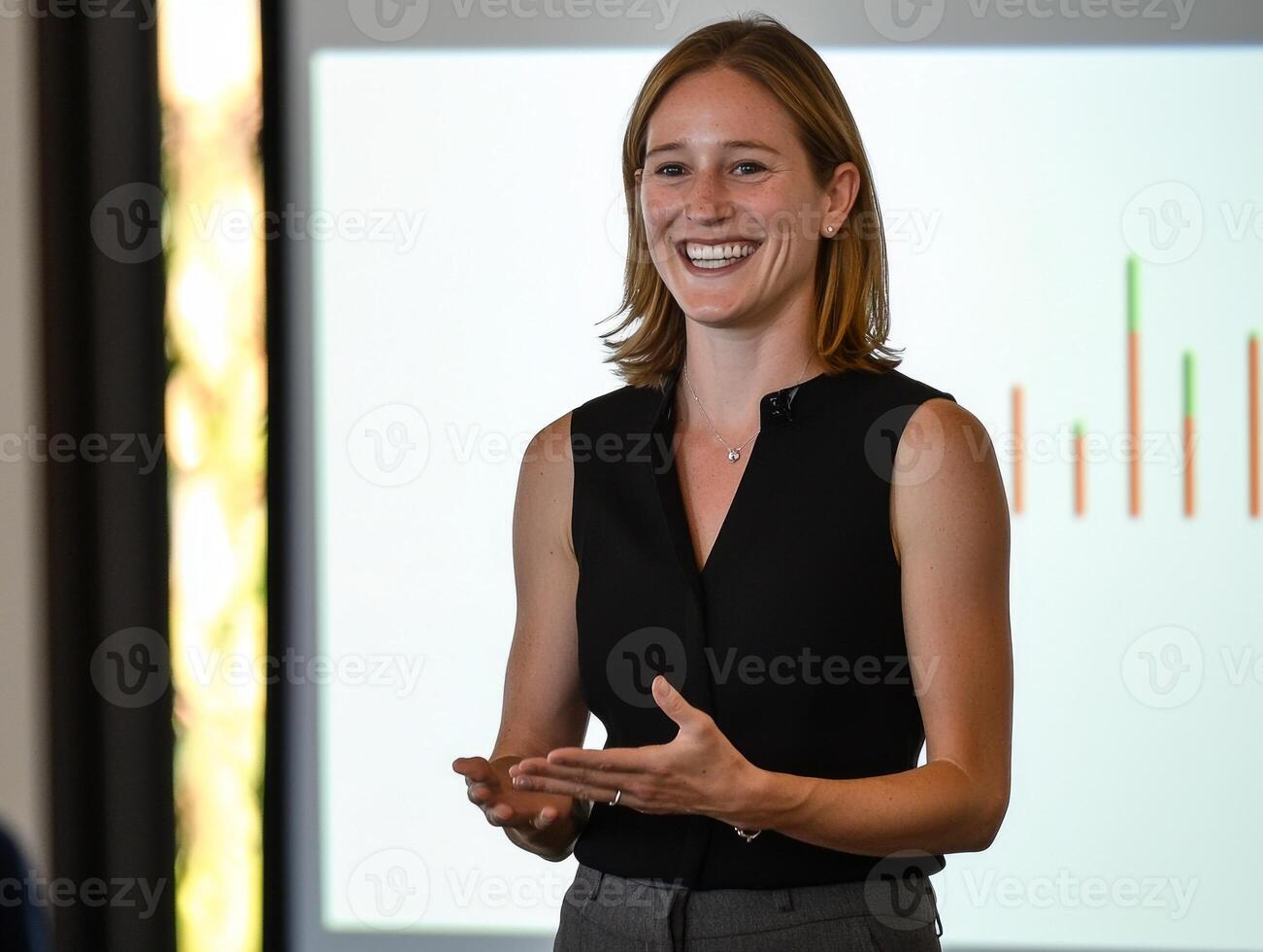 confident woman delivers a compelling pitch to investors highlighting key graphs on a projection screen in a minimalistic conference room surrounded by soft morning light. photo