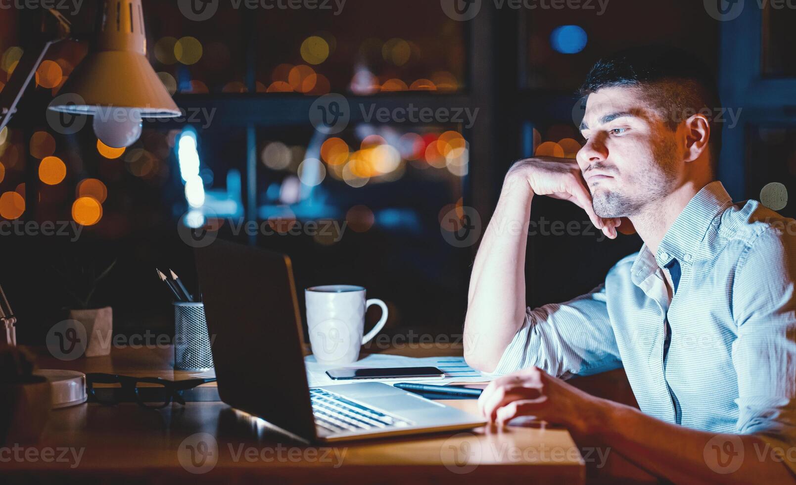 Boring Job. Overworked Business Guy Sitting At Laptop Uninterested In Work In Modern Office At Night. Low Light photo
