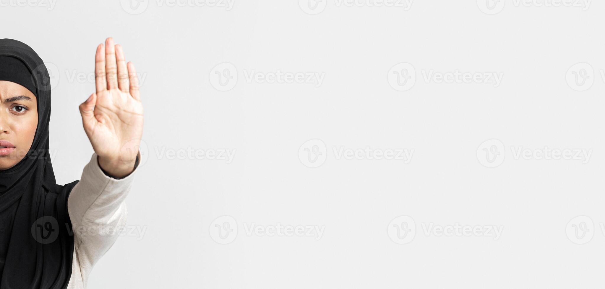 Refusal Concept. Serious afro islamic girl in headscarf making stop hand gesture with opened palms, standing over light gray background, panorama photo