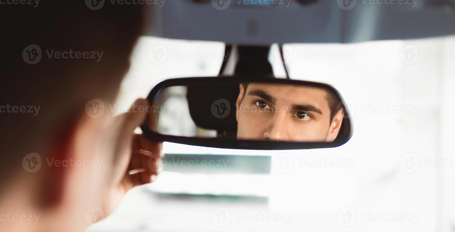 New Car Concept. Young Man Checking Mirrors Sitting In Driver's Seat Testing Buying Auto In Dealership Store photo