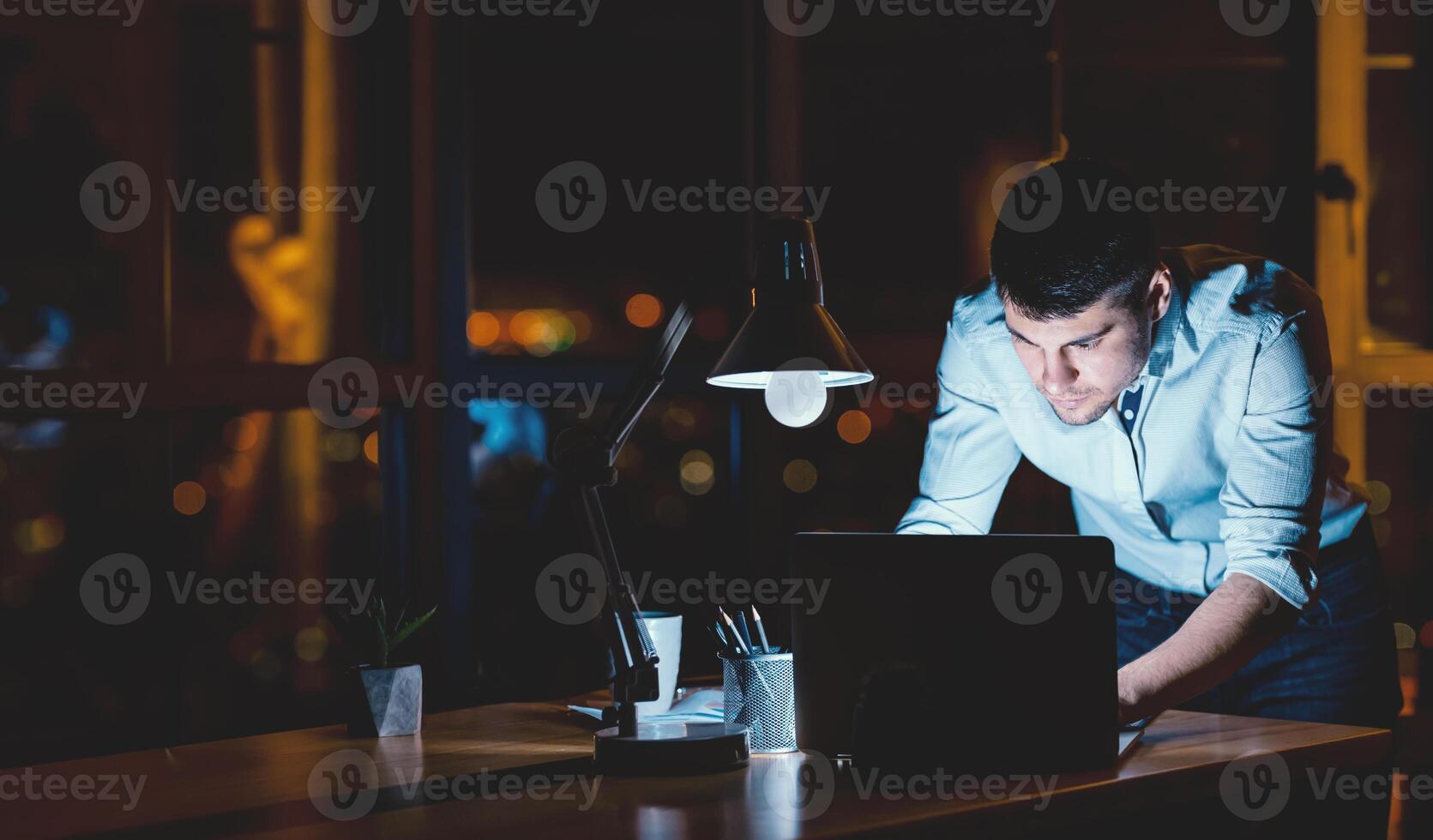 Hardworking Employee. Busy Businessman Working On Laptop Standing In Modern Office Late At Night. Free Space photo