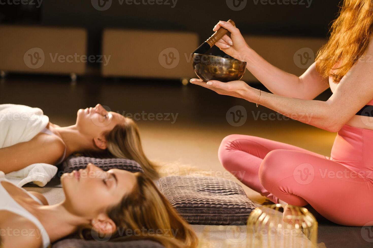 girls lying on the floor relax to the sounds of a Tibetan bowl in the fitness room photo