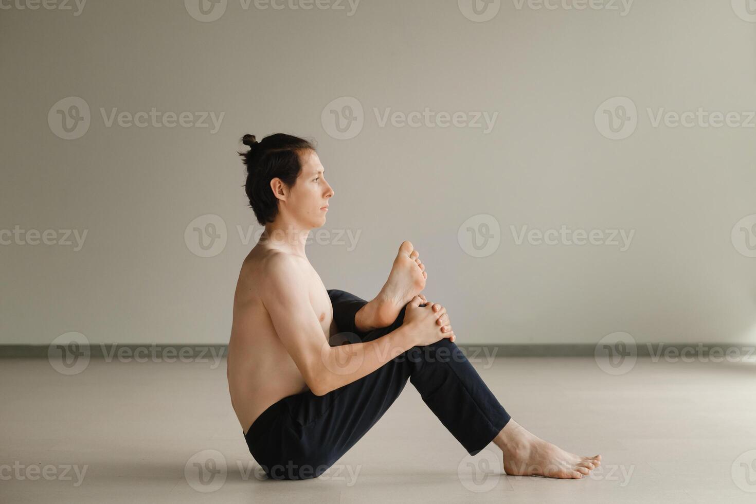 a man with a naked torso does yoga in the gym. the concept of a healthy lifestyle photo