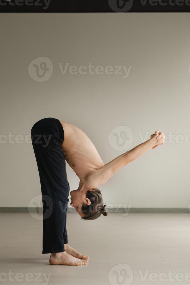 a man with a naked torso does yoga in the gym. the concept of a healthy lifestyle photo