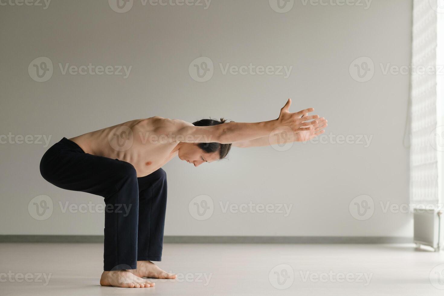 a man with a naked torso does yoga in the gym. the concept of a healthy lifestyle photo