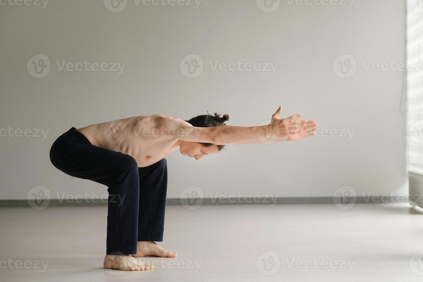 a man with a naked torso does yoga in the gym. the concept of a healthy lifestyle photo