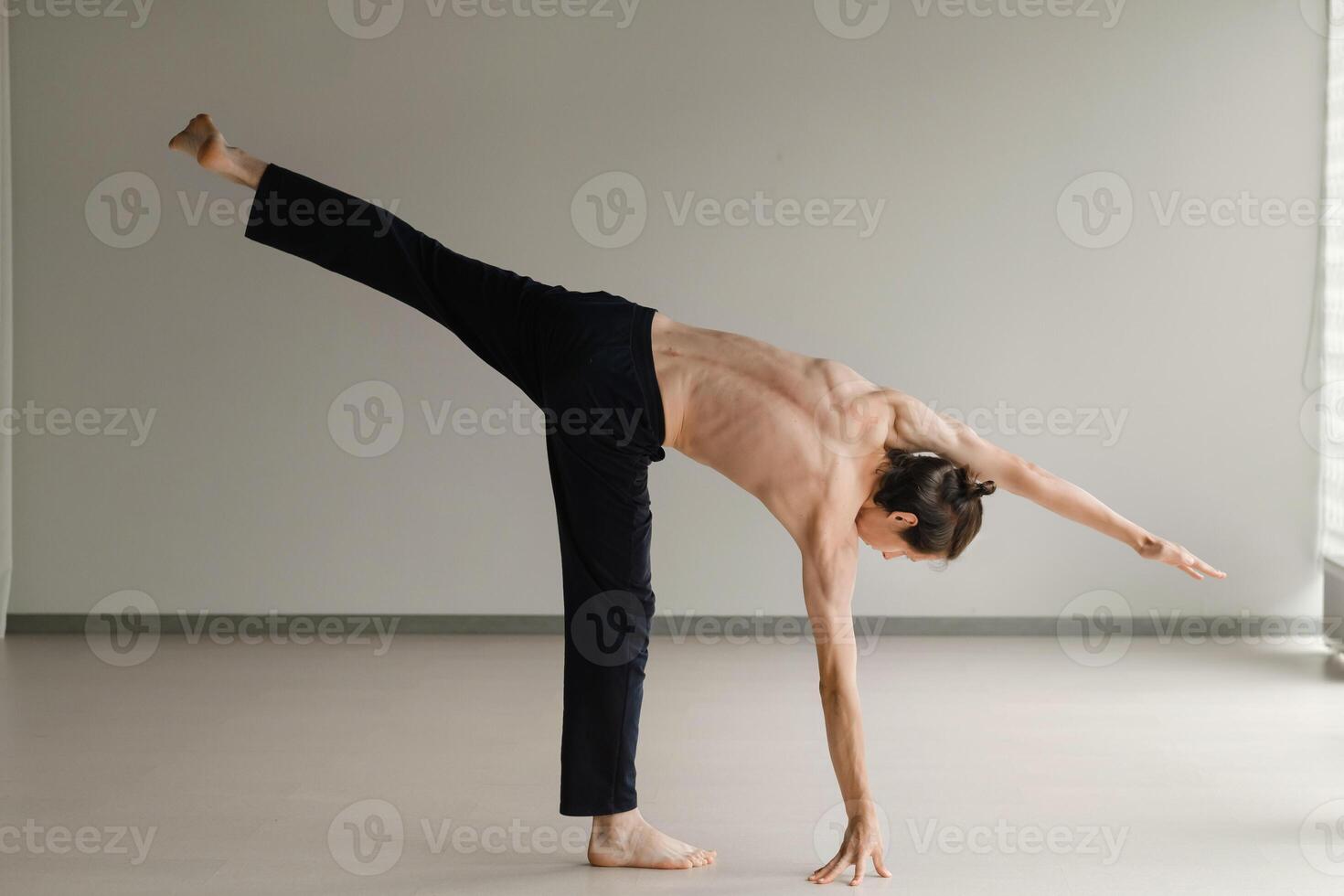 a man with a naked torso does yoga in the gym. the concept of a healthy lifestyle photo