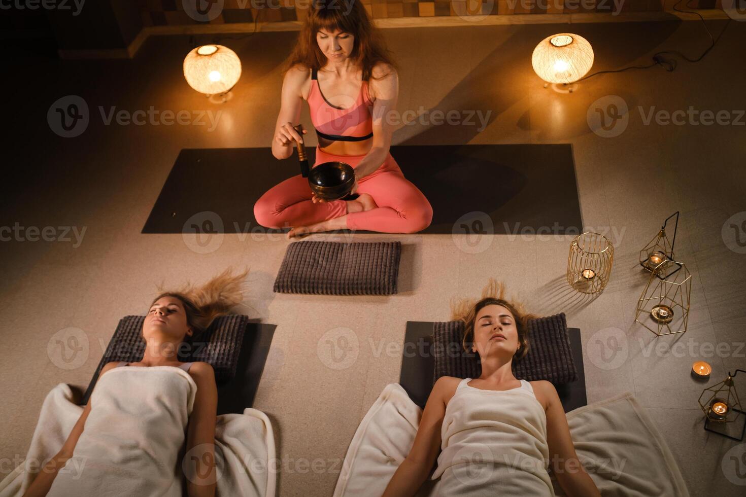 girls lying on the floor relax to the sounds of a Tibetan bowl in the fitness room photo