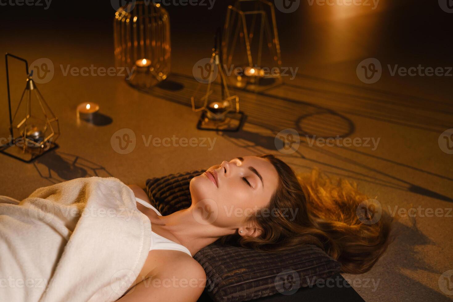 A woman lies on the floor covered with a blanket with her eyes closed and relaxes after a workout , shavasana pose photo