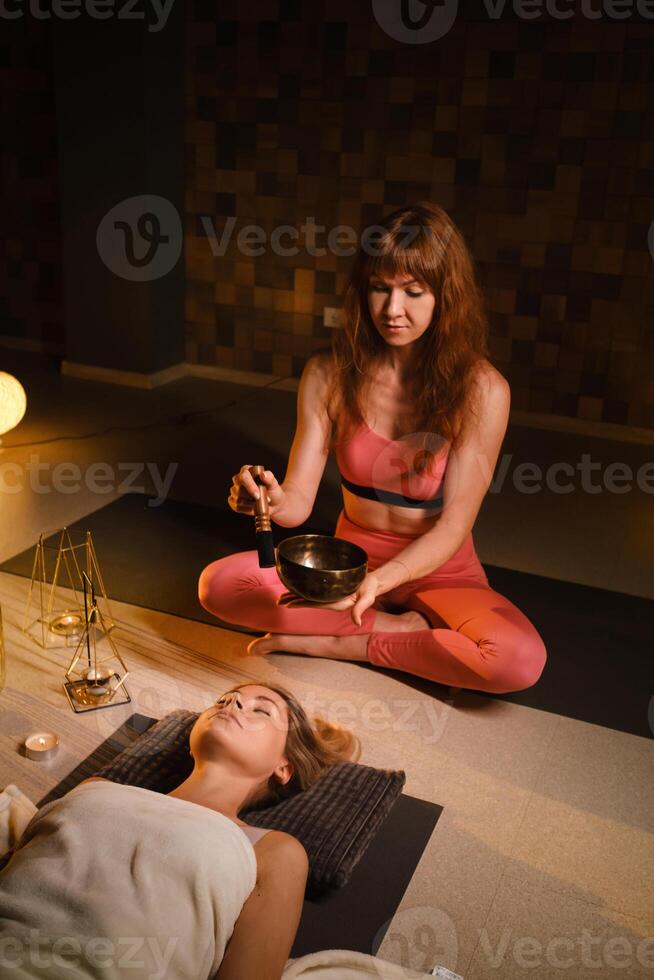 a girl lying on the floor relaxes to the sounds of a Tibetan bowl in the gym photo