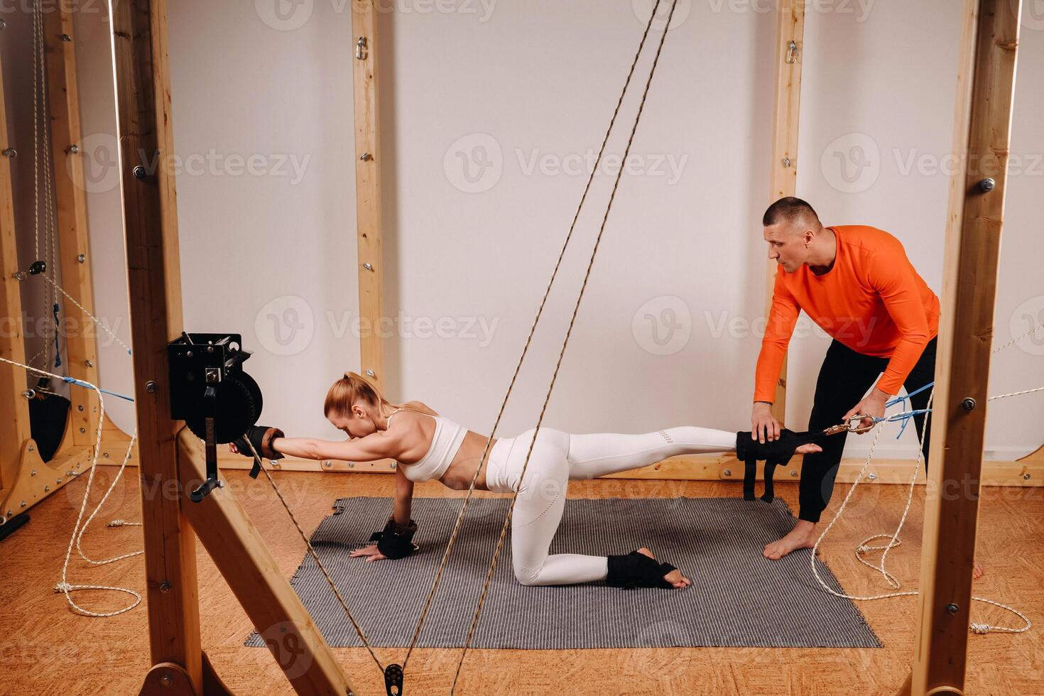 A trainer stretches a girl in a sports uniform on a simulator for stretching the human body photo
