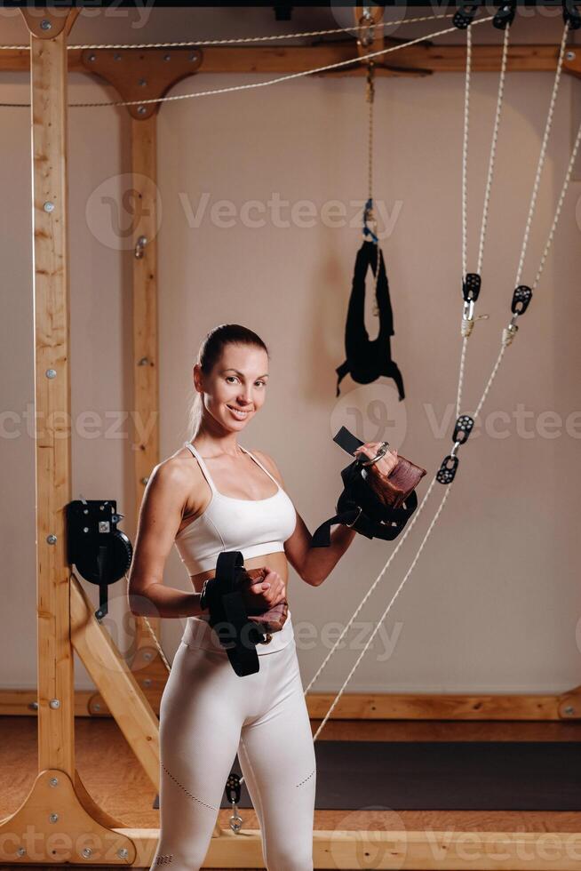 A girl in a sports uniform put devices on her hands for mounting on a simulator where she will do body stretching photo