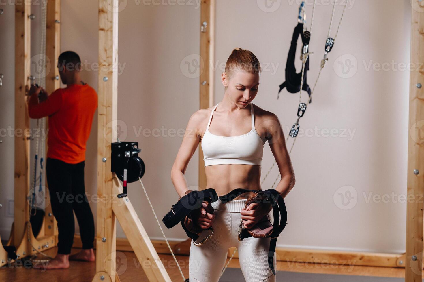 A girl in a sports uniform put devices on her hands for mounting on a simulator where she will do body stretching photo