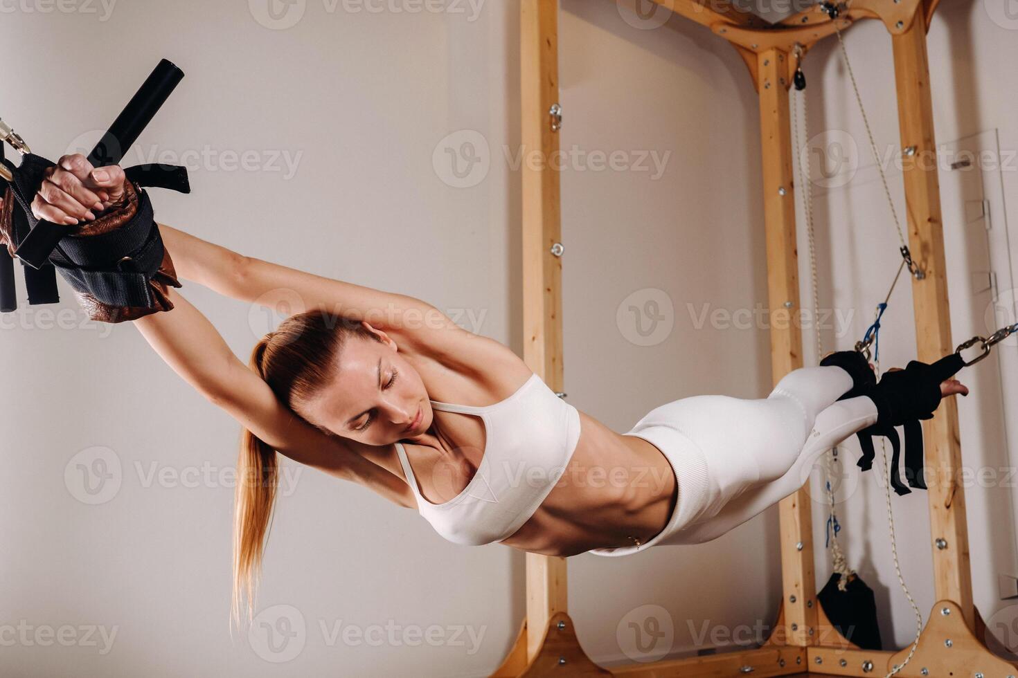 A girl in a sports uniform does exercises on a simulator for stretching the human body photo
