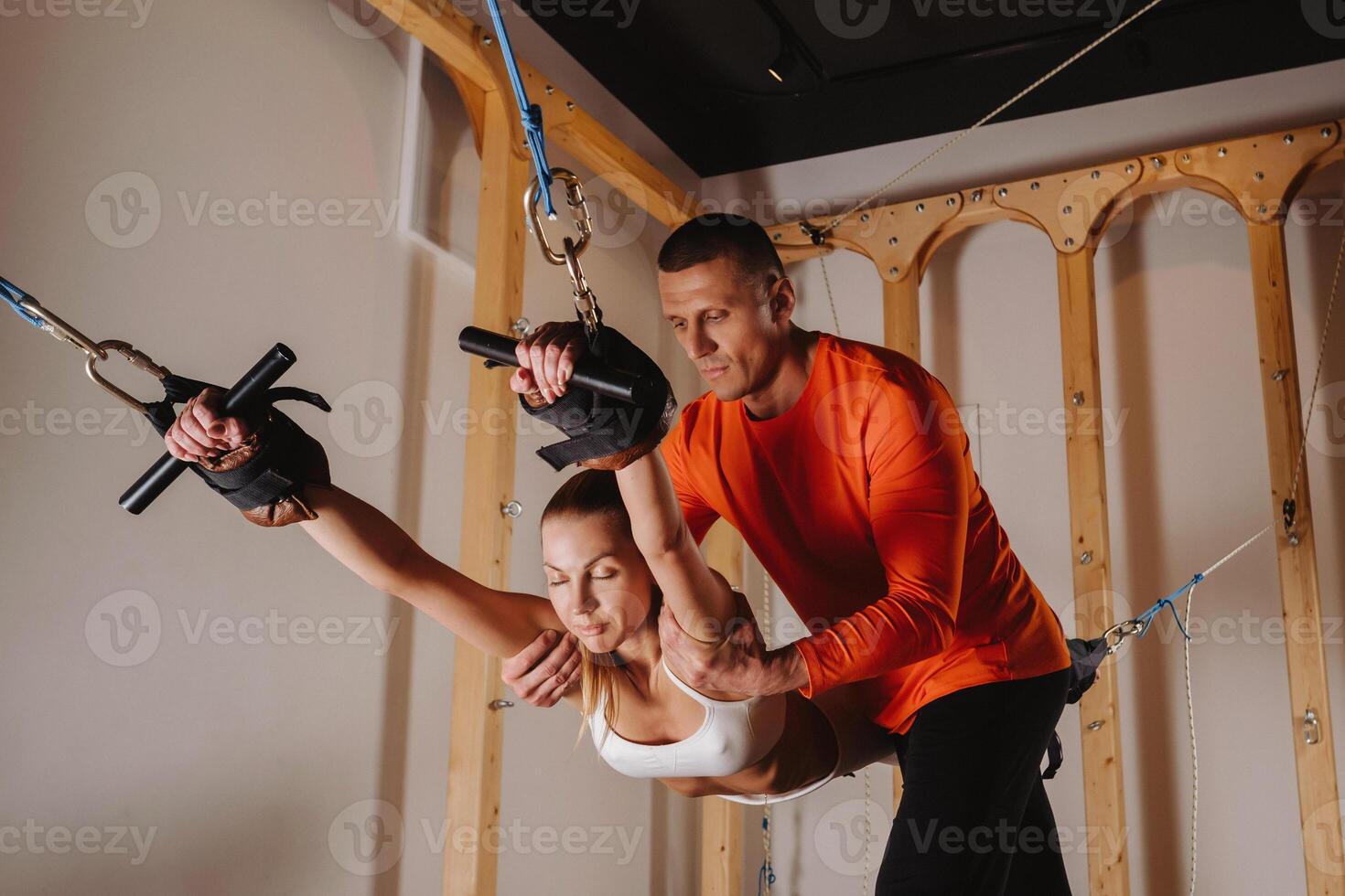 A trainer stretches a girl in a sports uniform on a simulator for stretching the human body photo