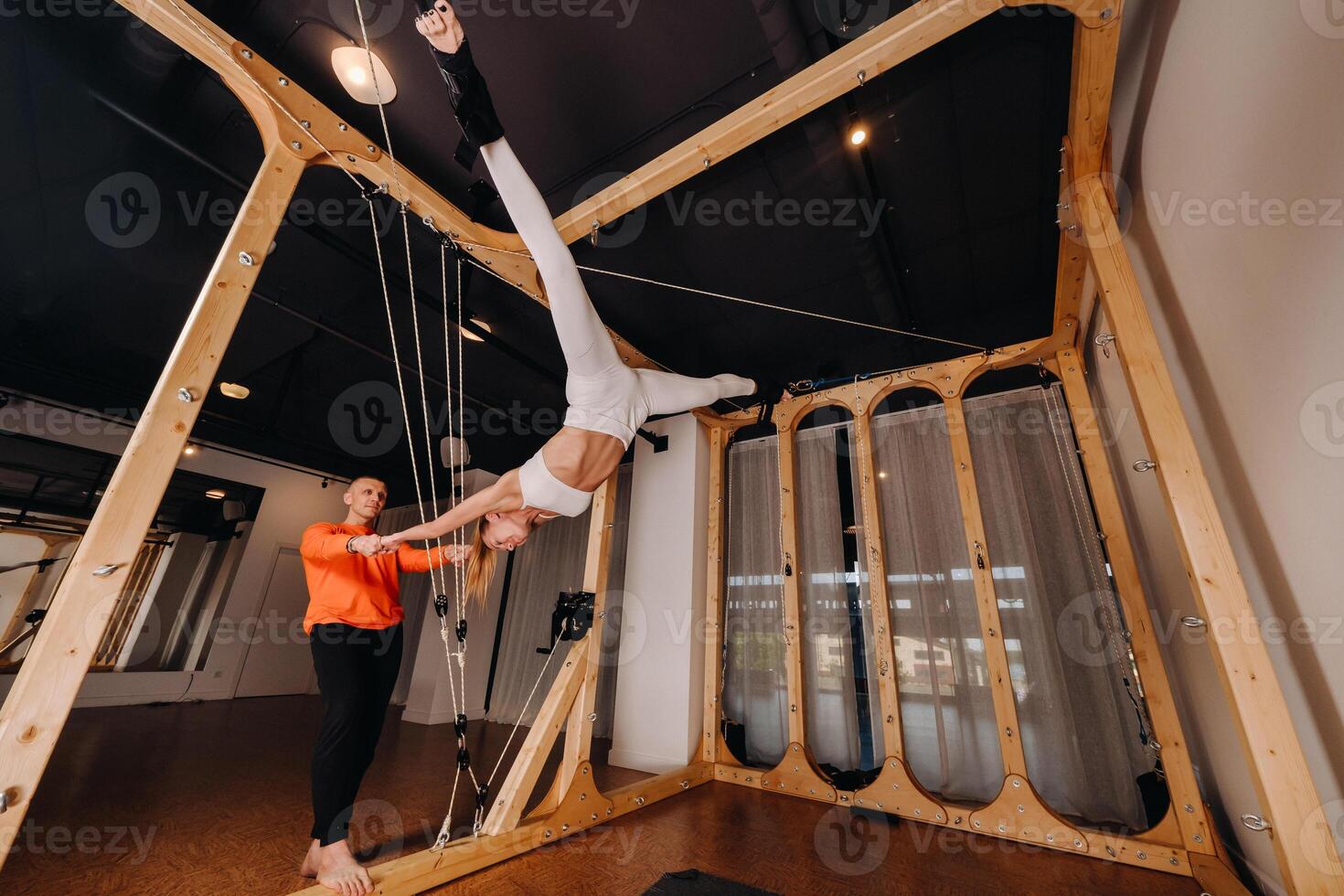 A trainer stretches a girl in a sports uniform on a simulator for stretching the human body photo