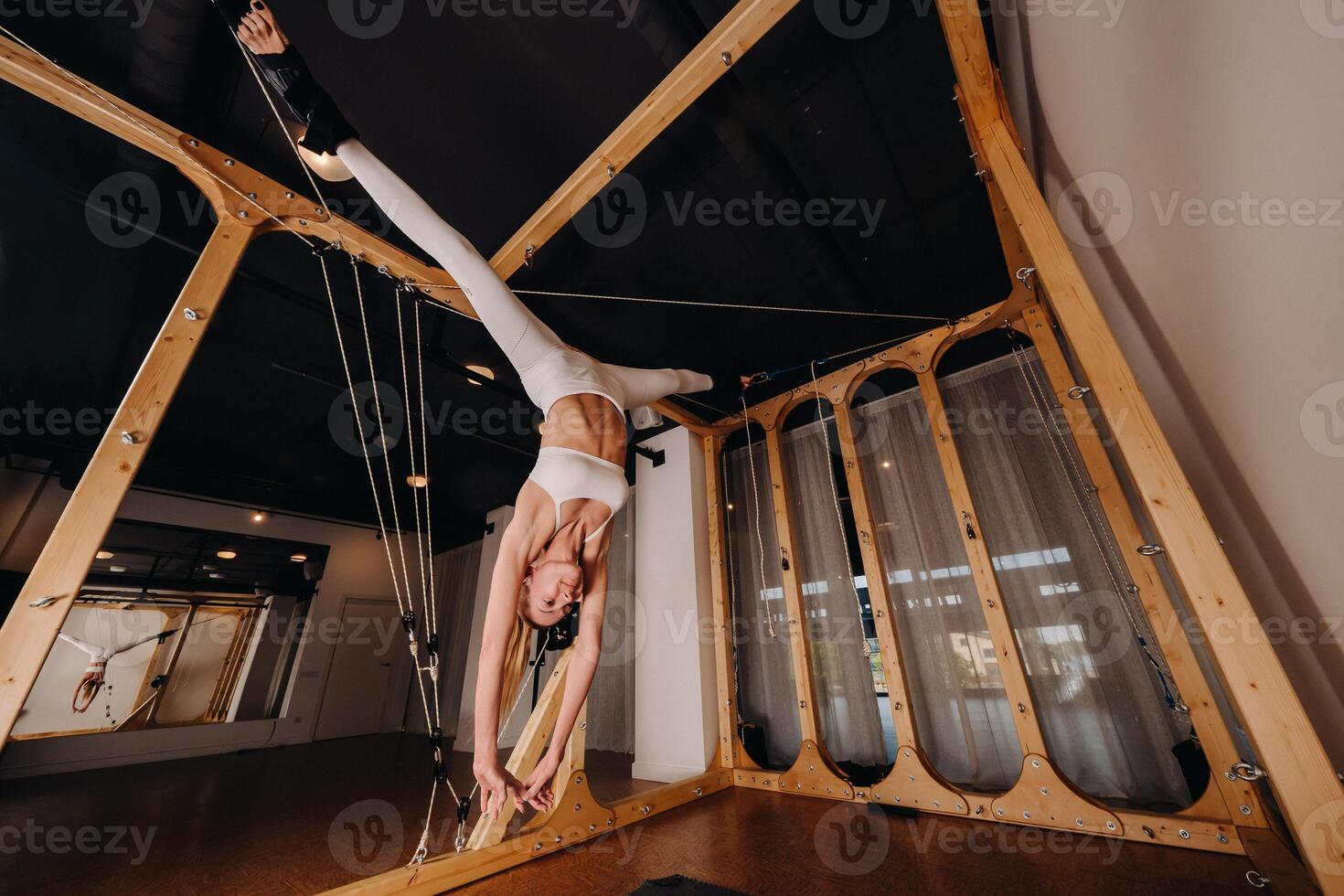 A girl in a sports uniform does exercises on a simulator for stretching the human body photo