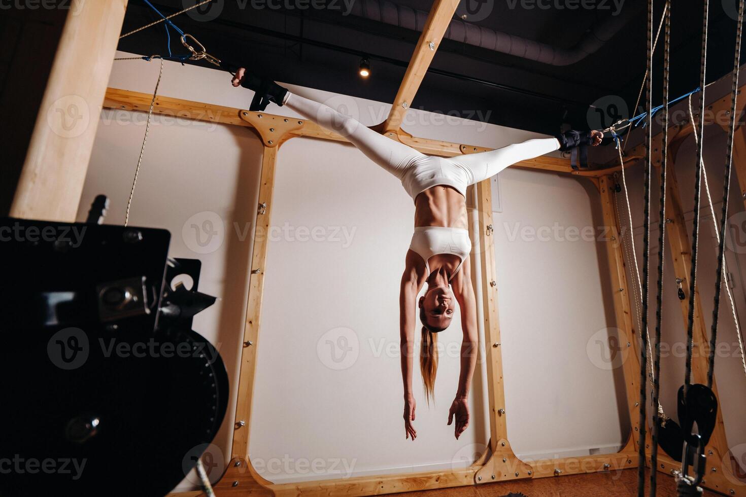 A girl in a sports uniform does exercises on a simulator for stretching the human body photo