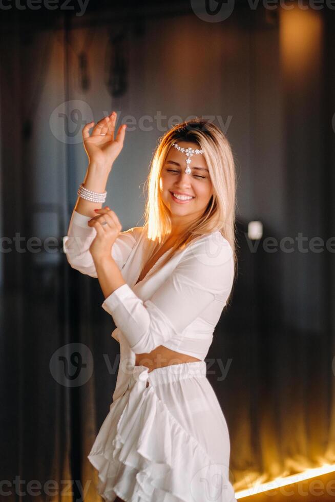 Beautiful smiling girl in a white dress dancing in the gym photo