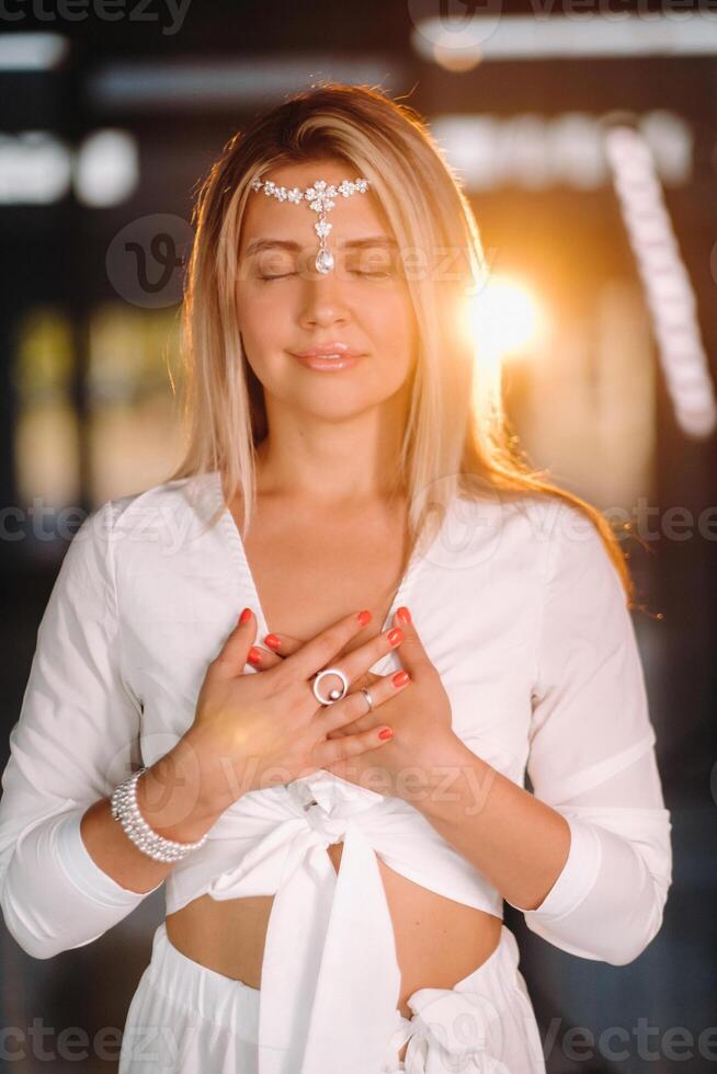 Portrait of a smiling girl in a white dress with her palms clasped in front of her photo
