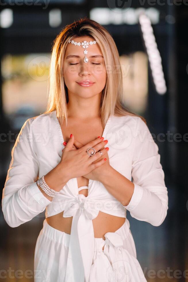 Portrait of a smiling girl in a white dress with her palms clasped in front of her photo