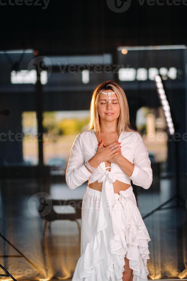 Portrait of a smiling girl in a white dress with her palms clasped in front of her photo