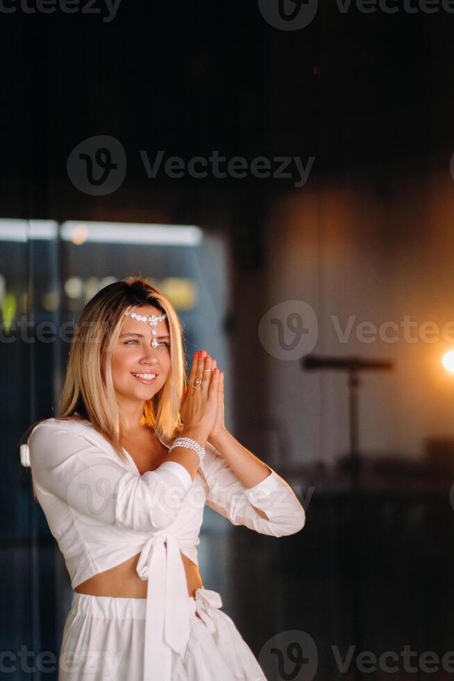 Portrait of a smiling girl in a white dress with her palms clasped in front of her photo