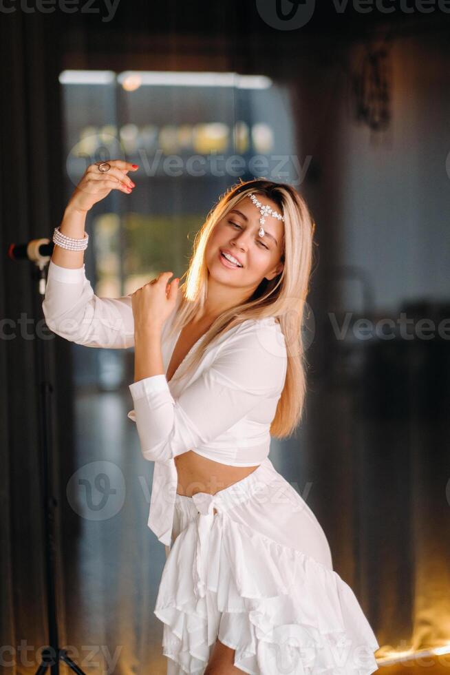 Beautiful smiling girl in a white dress dancing in the gym photo