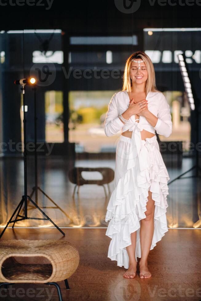 Portrait of a smiling girl in a white dress with her palms clasped in front of her photo