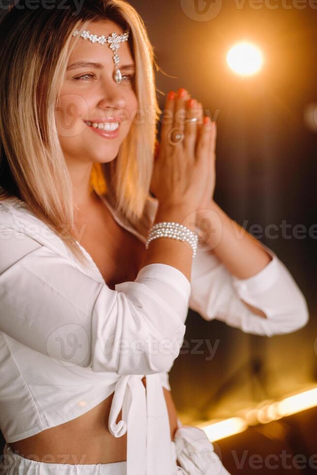 Portrait of a smiling girl in a white dress with her palms clasped in front of her photo