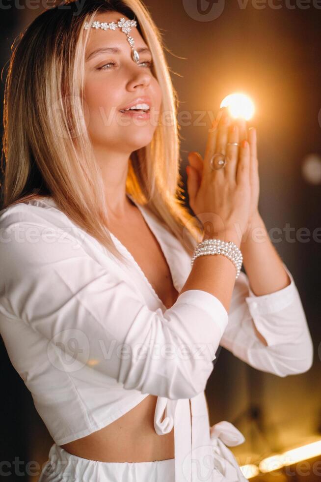 Portrait of a smiling girl in a white dress with her palms clasped in front of her photo
