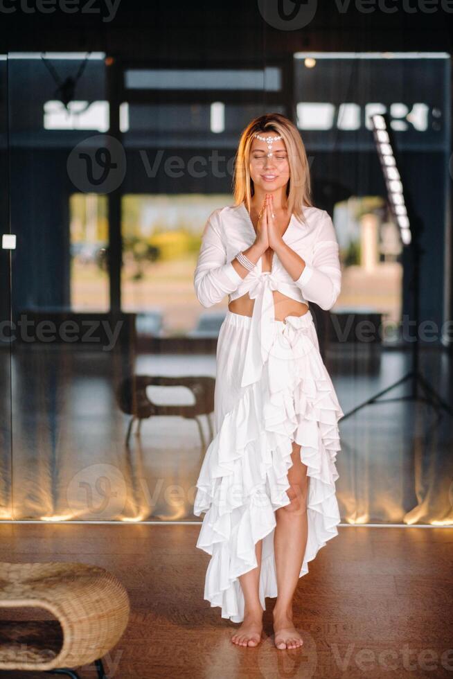 Portrait of a smiling girl in a white dress with her palms clasped in front of her photo
