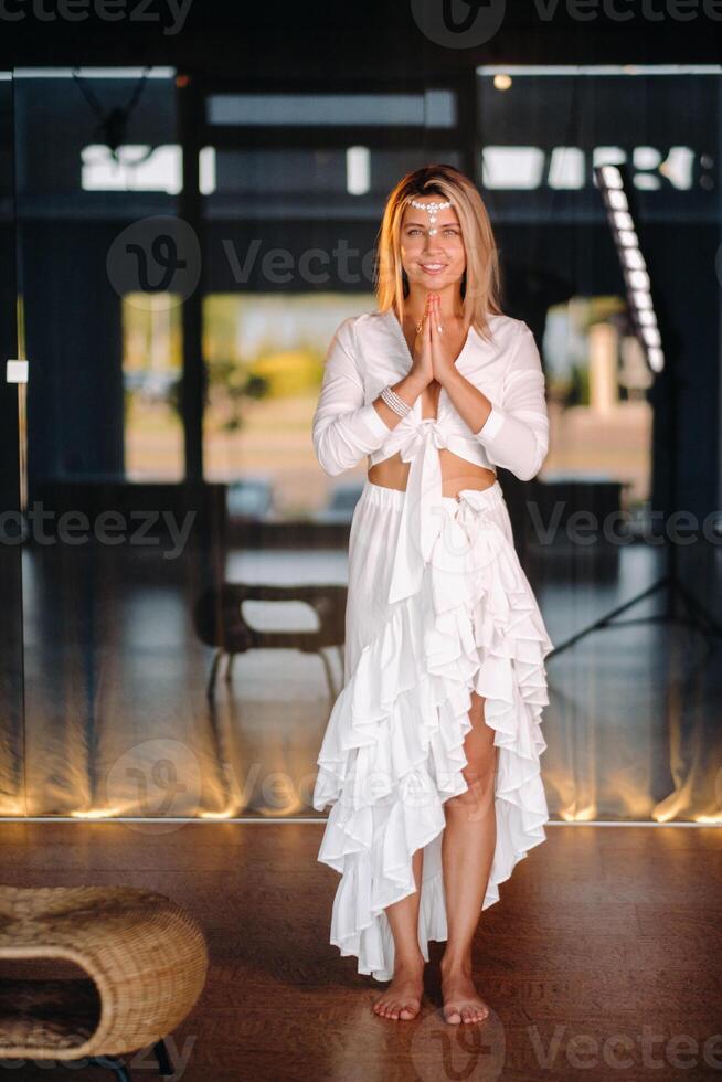 Portrait of a smiling girl in a white dress with her palms clasped in front of her photo