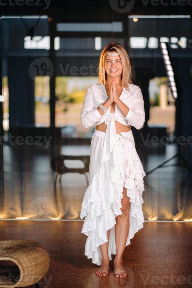 Portrait of a smiling girl in a white dress with her palms clasped in front of her photo