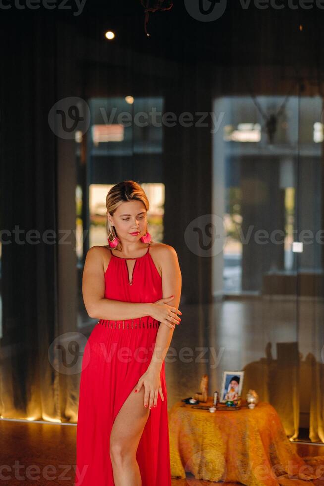 A girl in a red dress moves in a dance meditating indoors . Dynamic dance photo