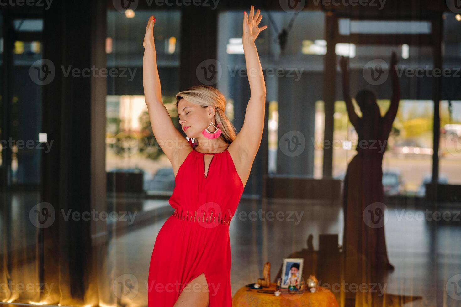 A girl in a red dress moves in a dance meditating indoors . Dynamic dance photo