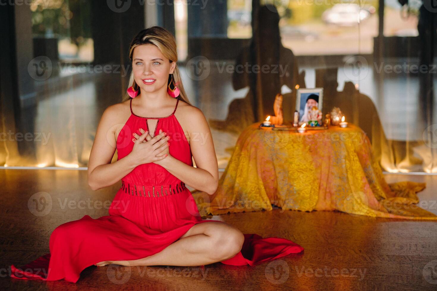Meditation and concentration. a woman in a red dress sitting on the floor is practicing medicine indoors . Calm and relaxation photo