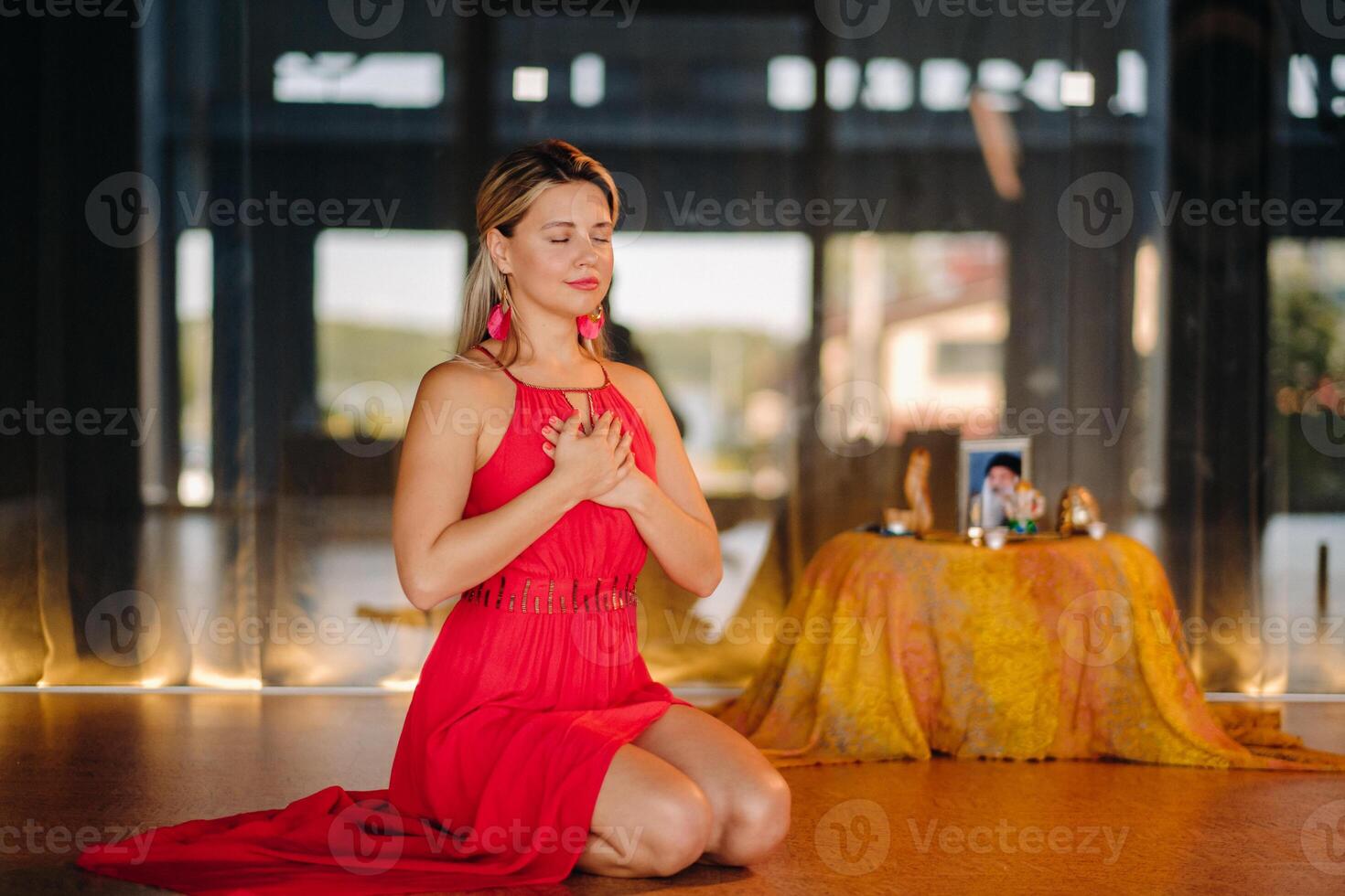 Meditation and concentration. a woman in a red dress, sitting on the floor with her eyes closed, is practicing medicine indoors. Peace and relaxation photo