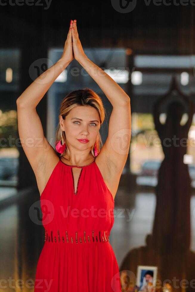 A girl in a red dress moves in a dance meditating indoors . Dynamic dance photo