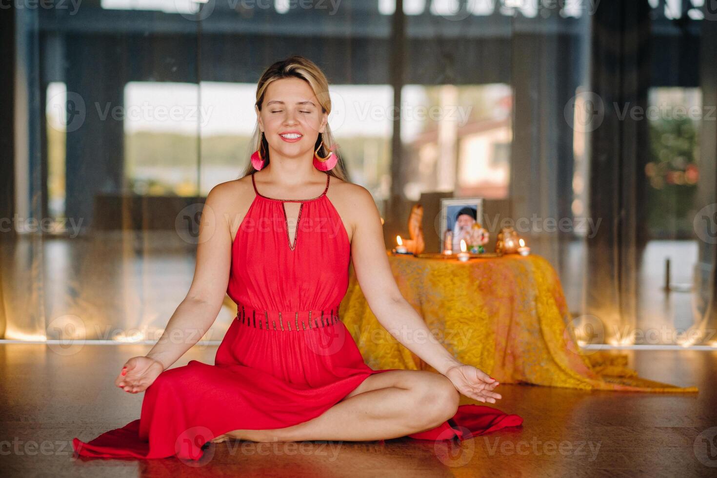 Meditation and concentration. a woman in a red dress, sitting on the floor with her eyes closed, is practicing medicine indoors. Peace and relaxation photo