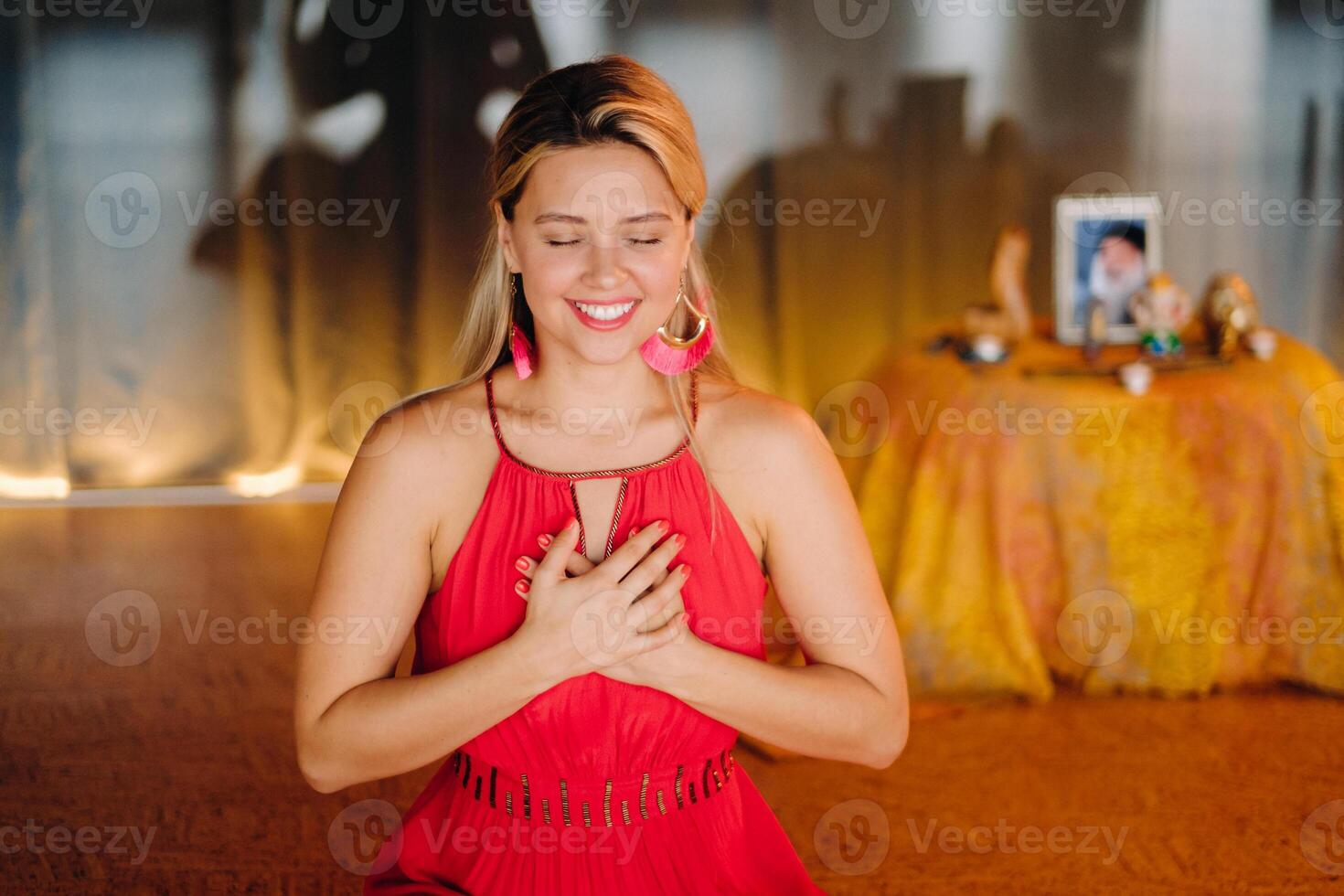 Meditation and concentration. a woman in a red dress, sitting on the floor with her eyes closed, is practicing medicine indoors. Peace and relaxation photo