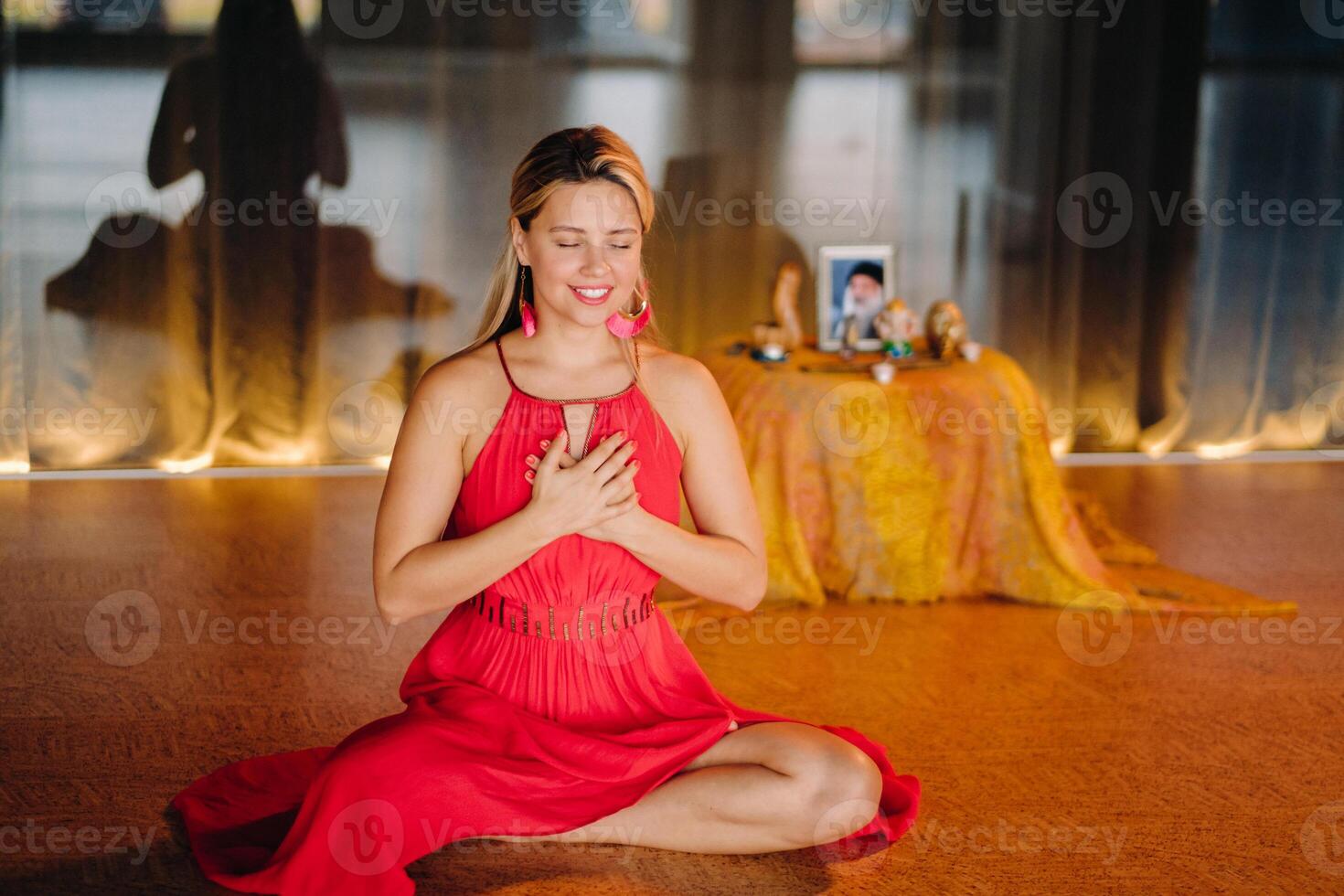 Meditation and concentration. a woman in a red dress, sitting on the floor with her eyes closed, is practicing medicine indoors. Peace and relaxation photo