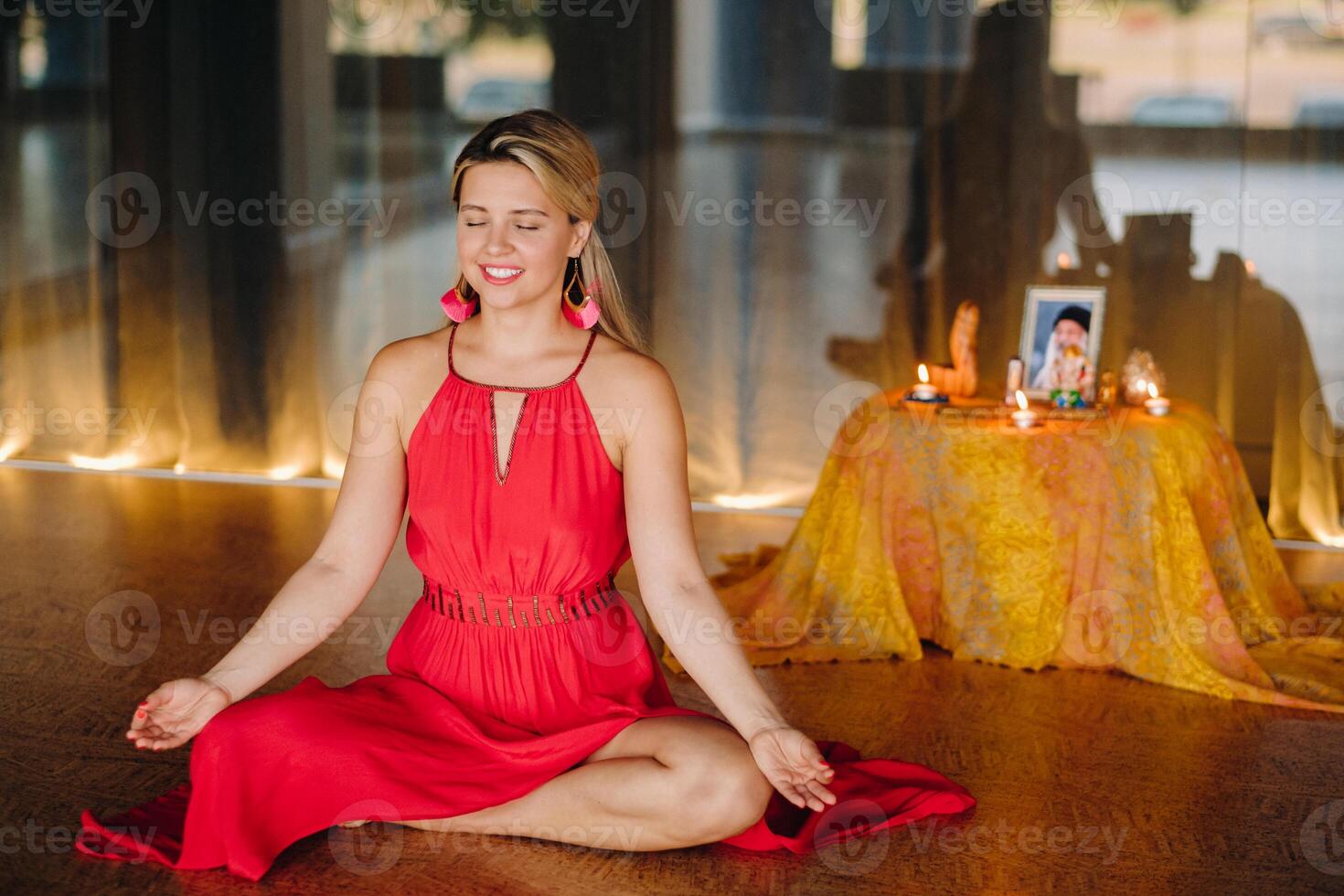 Meditation and concentration. a woman in a red dress, sitting on the floor with her eyes closed, is practicing medicine indoors. Peace and relaxation photo