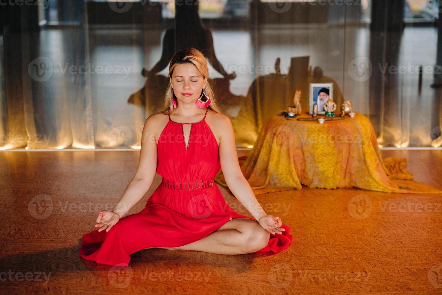 Meditation and concentration. a woman in a red dress, sitting on the floor with her eyes closed, is practicing medicine indoors. Peace and relaxation photo