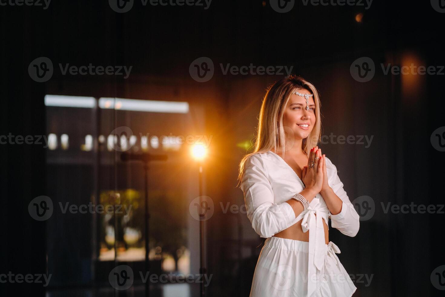 Portrait of a smiling girl in a white dress with her palms clasped in front of her photo